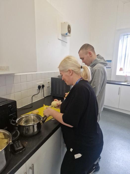 A resident and support worker cooking a meal together